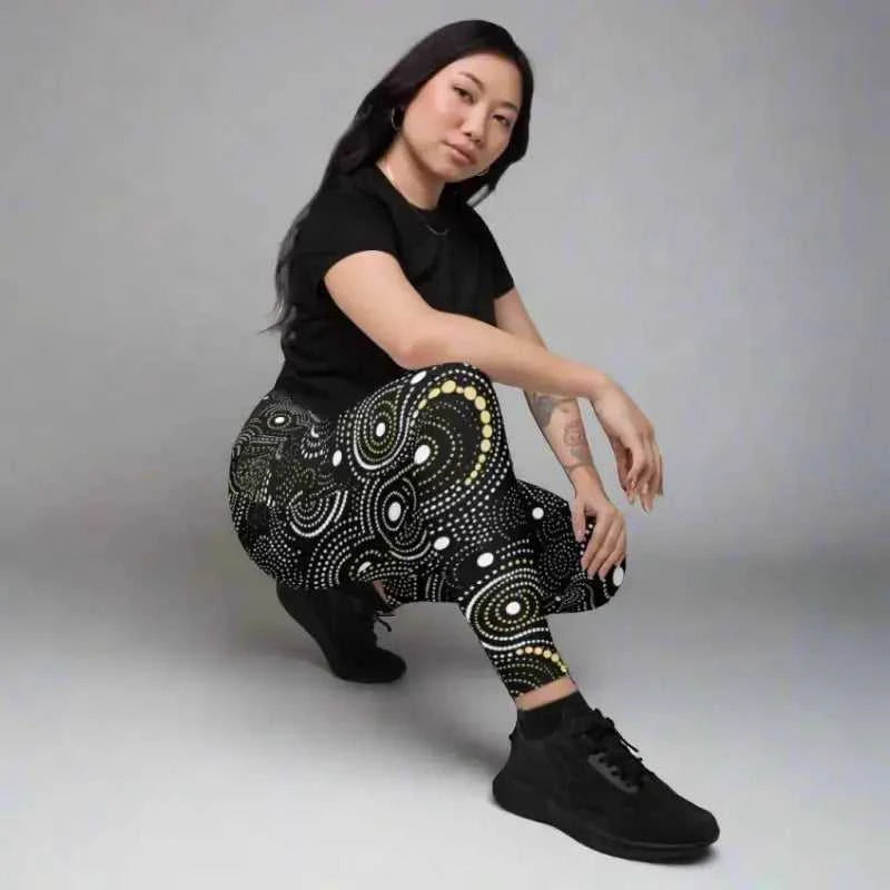 Woman wearing stylish crossover leggings in black and gold, perfect for workout and plus size activewear