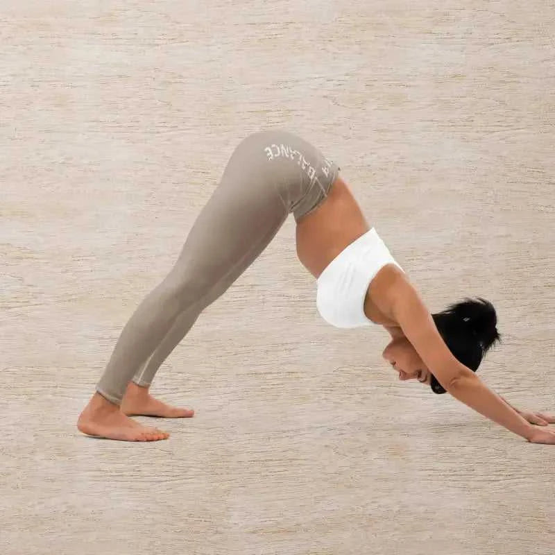 Woman in downward dog pose wearing khaki pilates leggings for a stylish workout look