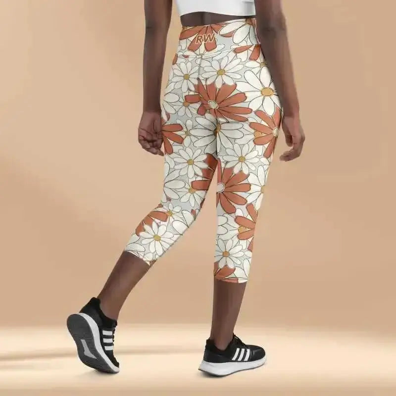 Floral print capri leggings with orange and white daisy pattern paired with black athletic shoes.