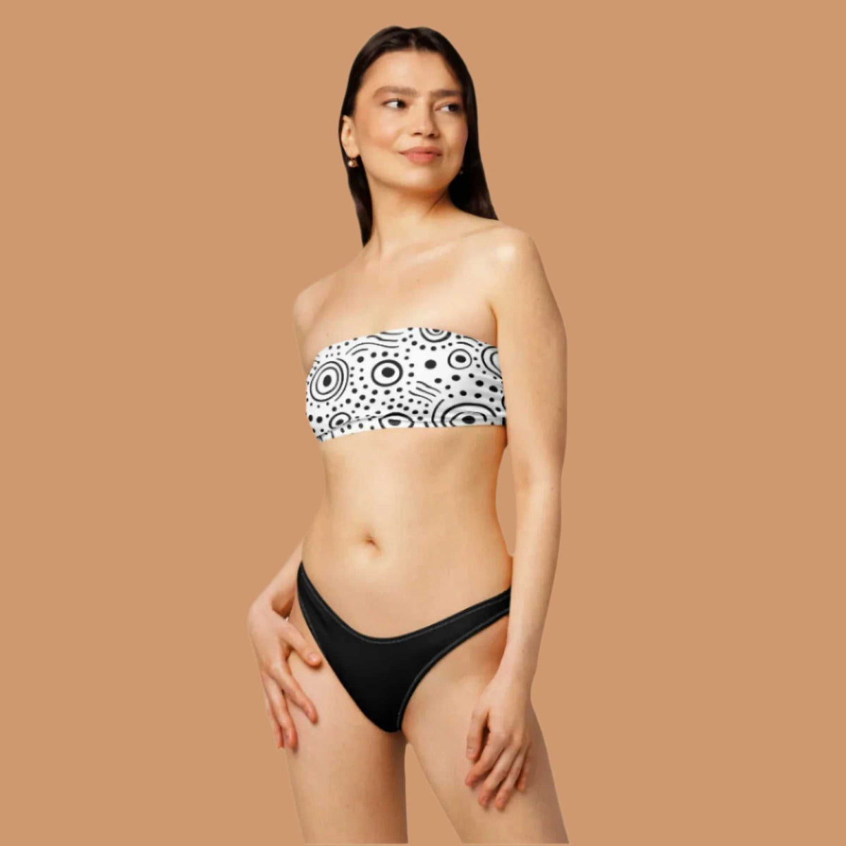 Woman wearing a black and white patterned bandeau top and black bottoms.