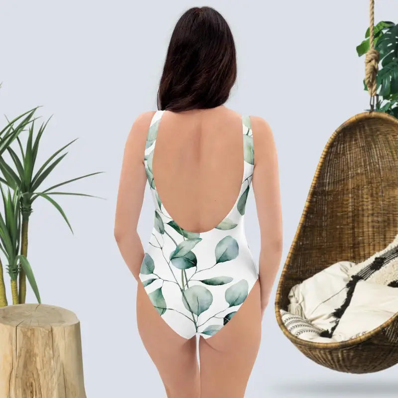 White one-piece swimsuit with green leaf print and low back design.