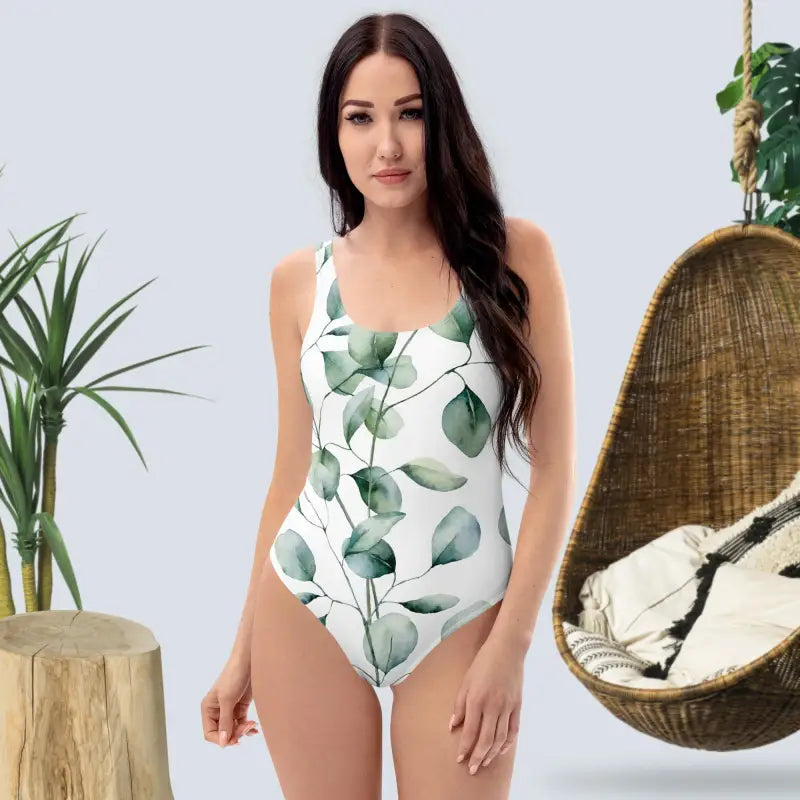 One-piece swimsuit with a green eucalyptus leaf print pattern on white fabric.