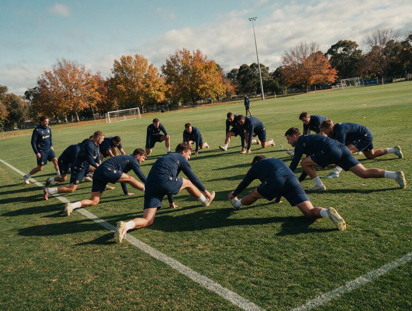 Soccer team in matching kits stretching on a field in Canberra